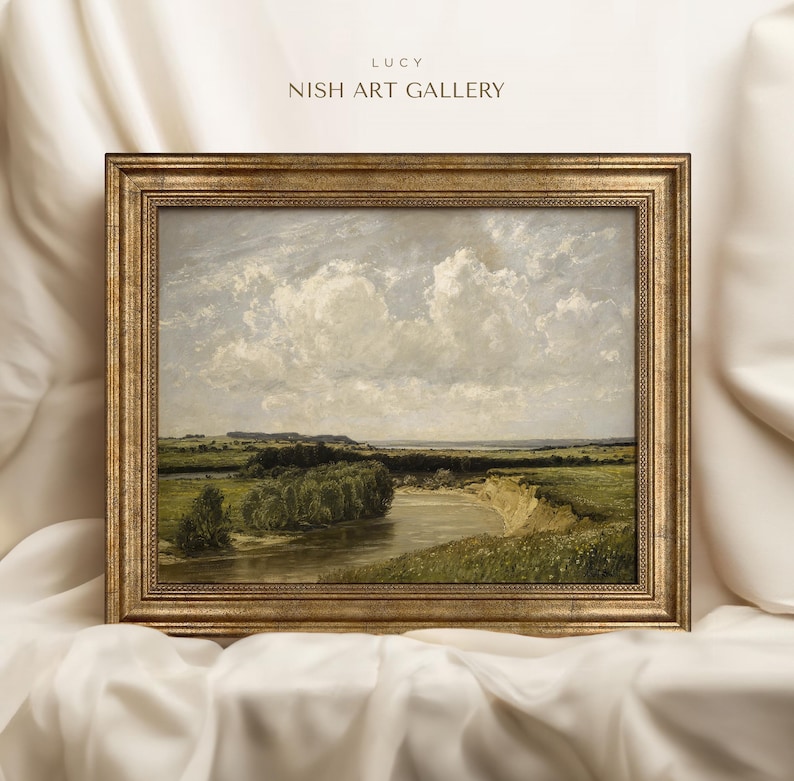 May include: A framed landscape painting depicting a river winding through a green field with a cloudy sky in the background. The frame is gold with a decorative border.