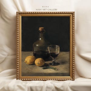 Könnte beinhalten: Ein gerahmtes Stillleben mit dem Titel REINA NISH ART GALLERY, das eine dunkle Glasflasche mit Korken, ein Glas Rotwein und zwei gelbe Zitronen auf einer hellen Oberfläche zeigt. Das Kunstwerk befindet sich in einem goldenen Perlenrahmen.