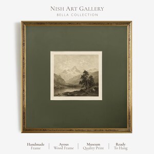 May include: A square framed wall art piece featuring a sepia-toned landscape print of mountains and a lake. The print is set within a dark olive green mount and a decorative gold-toned wooden frame. Text at the top reads Nish Art Gallery Bella Collection.