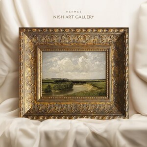 May include: A framed landscape painting depicting a river winding through a green field with a cloudy sky in the background. The frame is ornate and gold in color. The text "HERMES NISH ART GALLERY" is visible at the top of the image.