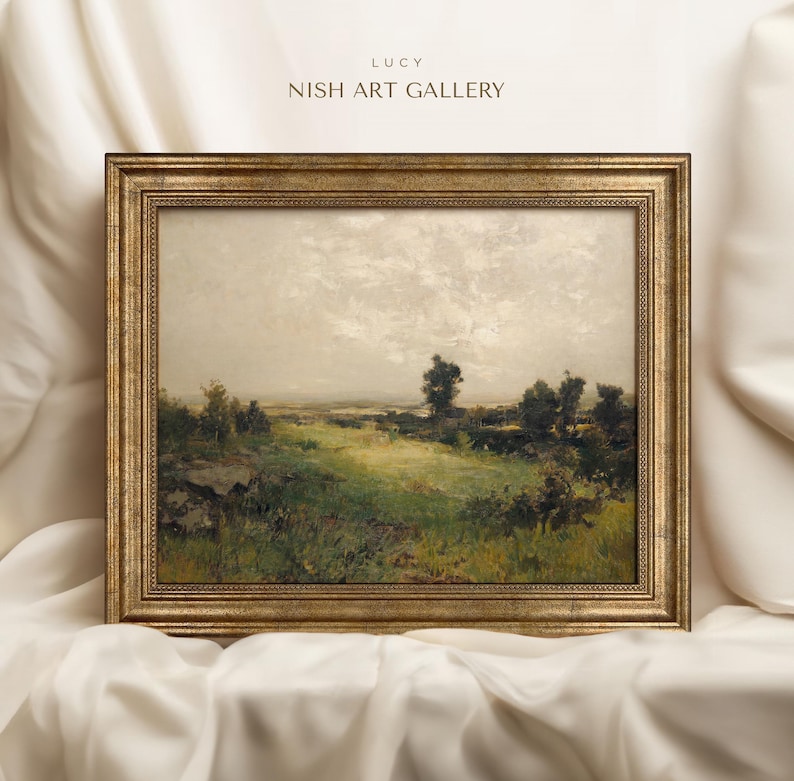 May include: A framed landscape painting depicting a rural scene with a field of green grass, trees, and a cloudy sky. The frame is gold with a decorative border.