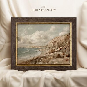 May include: Framed landscape art print featuring a coastal scene with a rocky cliff, beach, and ocean under a cloudy sky. The artwork is in a dark brown frame with a gold inner border. The text "ARES NISH ART GALLERY" is at the top.