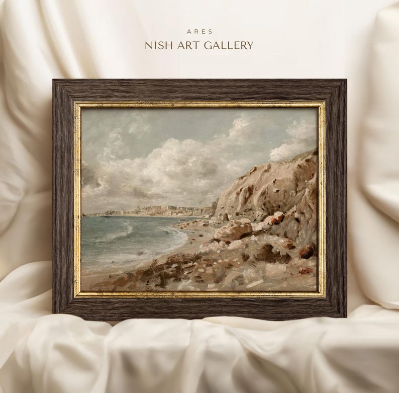 May include: Framed landscape art print featuring a coastal scene with a rocky cliff, beach, and ocean under a cloudy sky. The artwork is in a dark brown frame with a gold inner border. The text "ARES NISH ART GALLERY" is at the top.