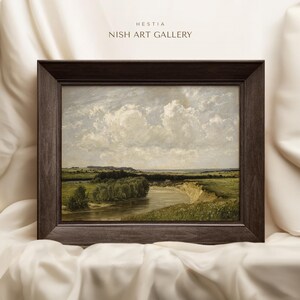 May include: A framed painting depicting a landscape with a river winding through a field. The sky is a light blue with fluffy white clouds. The painting is in a dark brown frame.