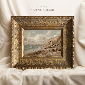 May include: A framed landscape painting of a coastal scene with a rocky cliff, beach, and ocean under a cloudy sky. The ornate gold frame features detailed carvings. The text "HERMES NISH ART GALLERY" is at the top.