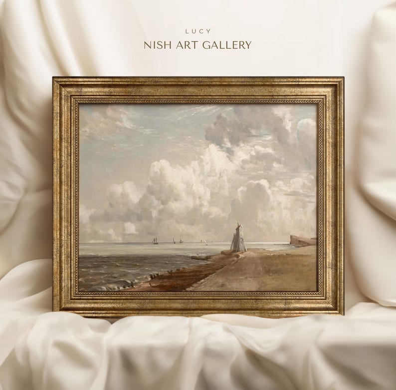 May include: A framed painting depicting a seascape with a lighthouse on a rocky shore. The sky is filled with fluffy white clouds, and the sea is a calm blue. The painting is in a gold frame.