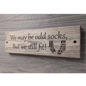 May include: Wooden sign with the text "We may be odd socks, But we still fit!" and two sock shapes with stars.