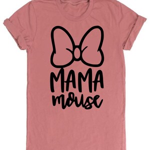 Op de afbeelding: Een roze T-shirt met een zwarte strik en de tekst "MAMA mouse" erop gedrukt.