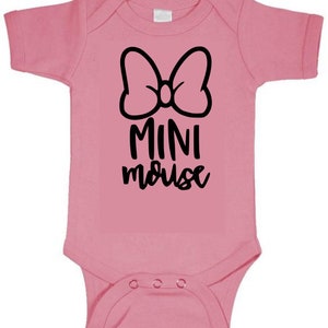 Op de afbeelding: Roze baby onesie met een zwarte strik en de tekst "MINI mouse" in zwart.