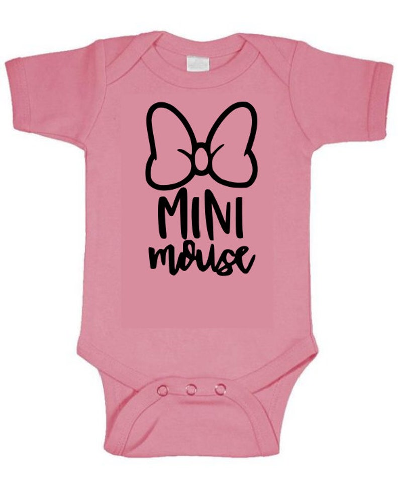 Op de afbeelding: Roze baby onesie met een zwarte strik en de tekst "MINI mouse" in zwart.