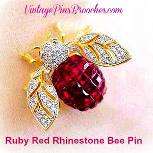 May include: Ruby red rhinestone bee pin with gold wings and clear rhinestones. The bee is in flight with its wings spread.