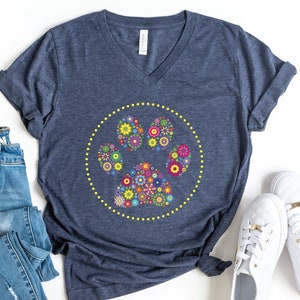 May include: A navy blue t-shirt featuring a floral paw print design. The paw print is encircled by a yellow circle with yellow dots.