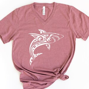 May include: A mauve v-neck t-shirt with a white tribal shark design.