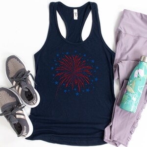 Puede incluir: Un top de tirantes azul marino con un gr&aacute;fico de fuegos artificiales rojo y azul. El top de tirantes se combina con zapatillas deportivas grises, leggings lavanda y una botella de agua turquesa con dise&ntilde;o floral.
