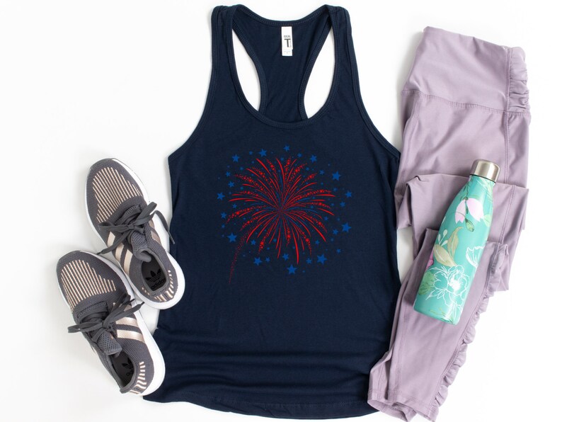 Puede incluir: Un top de tirantes azul marino con un gr&aacute;fico de fuegos artificiales rojo y azul. El top de tirantes se combina con zapatillas deportivas grises, leggings lavanda y una botella de agua turquesa con dise&ntilde;o floral.