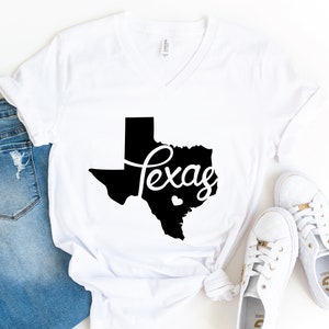 Puede incluir: Camiseta blanca con un contorno negro del estado de Texas y la palabra "Texas" escrita en cursiva.