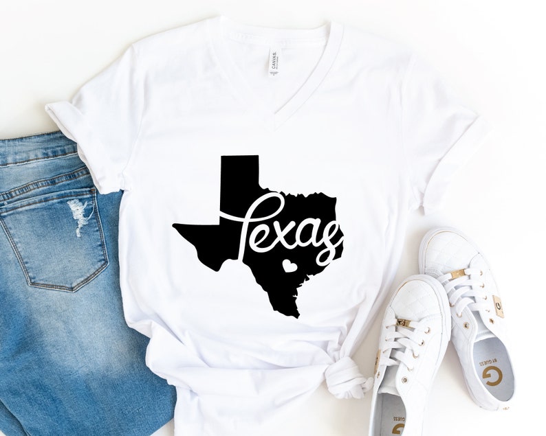 Puede incluir: Camiseta blanca con un contorno negro del estado de Texas y la palabra "Texas" escrita en cursiva.