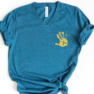 May include: A teal blue v-neck t-shirt with a gold handprint with a ribbon inside.