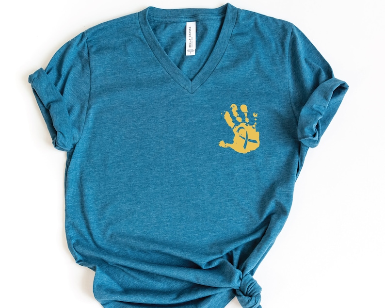 May include: A teal blue v-neck t-shirt with a gold handprint with a ribbon inside.