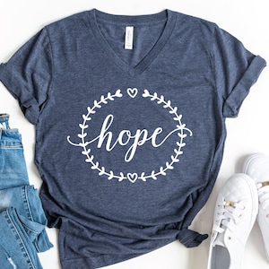 May include: A navy blue t-shirt with a white graphic of a wreath with the word "hope" in the center.