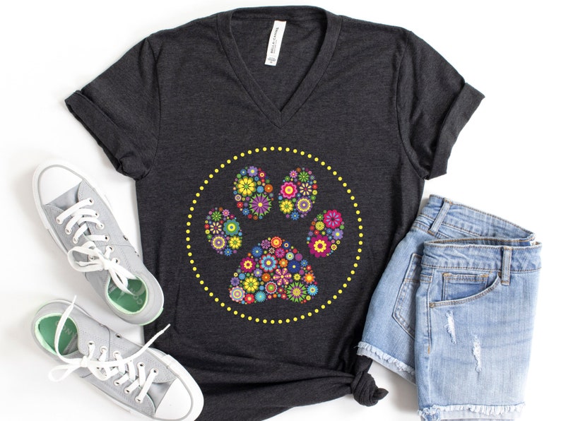 May include: A dark grey V-neck t-shirt featuring a floral paw print design. The paw print is encircled by a yellow dotted circle.