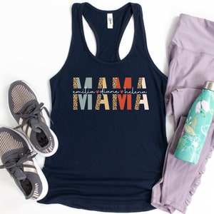 May include: Navy blue tank top with the text "MAMA" in colorful block letters with a leopard print design. The text "emilia ♥ diane ♥ helena" is written in smaller letters below the word "MAMA".