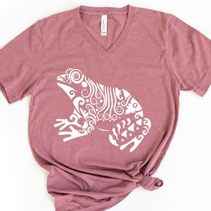 May include: A mauve v-neck t-shirt with a white stylized frog design.