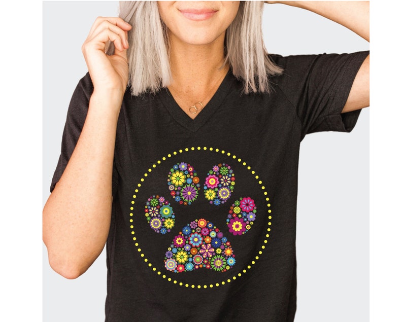 May include: Black V-neck t-shirt with a yellow circle design featuring a colourful floral paw print.