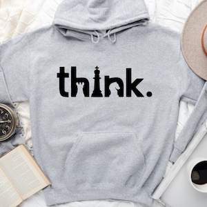May include: A grey hooded sweatshirt with the word "think" printed in black. The word is stylised with a chess piece in the middle of the word.