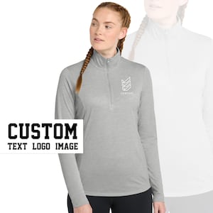 May include: A grey long-sleeved shirt with a mock neck and a zip. The shirt has a white logo on the chest that says "COMPANY" with a geometric design. The text "CUSTOM TEXT LOGO IMAGE" is in black letters on a white background.