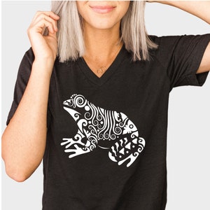 May include: A black v-neck t-shirt with a white stylized design of a frog with intricate details.