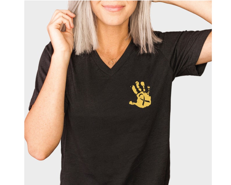 May include: Black v-neck t-shirt with a gold handprint design featuring a gold ribbon.