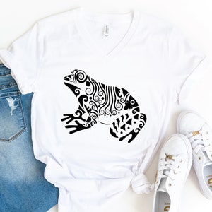 May include: White V-neck t-shirt with a black and white stylized illustration of a frog with intricate details.