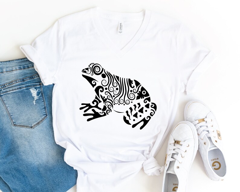 May include: White V-neck t-shirt with a black and white stylized illustration of a frog with intricate details.