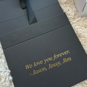 May include: Black gift box with a gold inscription that reads "We love you forever. - Jason, Jessy, Jim"