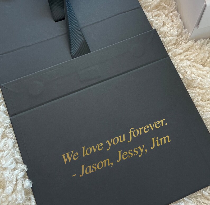 May include: Black gift box with a gold inscription that reads "We love you forever. - Jason, Jessy, Jim"