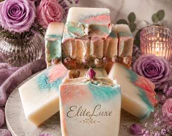 May include: Artisan soap bars with pastel colors of pink, blue, and white, arranged on a marble tray. The soap is decorated with a floral design and the text "Elite Luxe". The image includes pink and purple roses and petals.