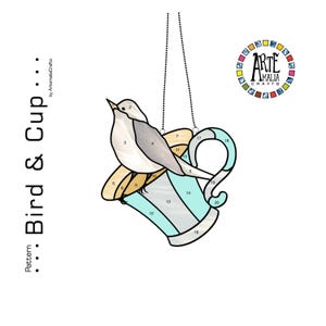 K&ouml;nnte beinhalten: Glasmalerei eines Vogels auf einer Tasse, in Hellblau- und Beiget&ouml;nen. Das Design enth&auml;lt den Text "Bird & Cup" und den Namen des K&uuml;nstlers. Das Kunstwerk wird von einer Kette gehalten.