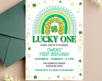 May include: A white invitation with a green and yellow rainbow design. The text "Lucky One" is in yellow with green outlines. The text "Owen's First Birthday" is in black. The invitation includes the date, time, and location of the party. The text "Please RSVP to Angie at 123.456.7890" is at the bottom of the invitation.