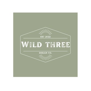 May include: A white logo on a sage green background. The logo is a hexagon with a starburst design at the top and bottom. The text inside the hexagon reads "WILD THREE DESIGN CO. EST 2022".