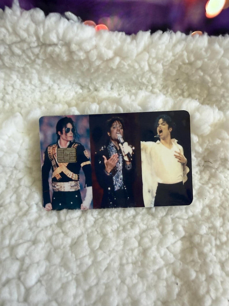 May include: A rectangular payment card featuring three distinct photographic images of Michael Jackson. The left image shows him in a military-style jacket, the center in a sequined shirt with a microphone, and the right in a white shirt.
