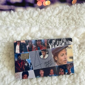 May include: A rectangular credit card featuring a collage of Michael Jackson images from the Thriller era. The design includes a large number 40, the text Michael Jackson Thriller, and the letters PYT. A metallic chip is visible on the left side.