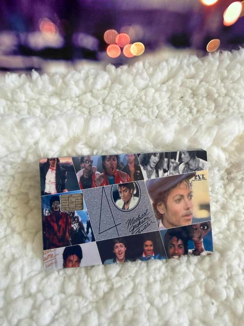 May include: A rectangular credit card featuring a collage of Michael Jackson images from the Thriller era. The design includes a large number 40, the text Michael Jackson Thriller, and the letters PYT. A metallic chip is visible on the left side.