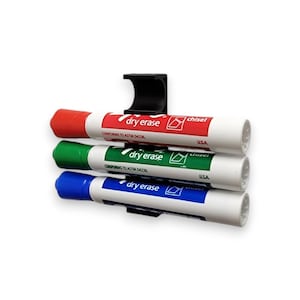 May include: A black marker holder with three dry erase markers. The markers are red, green, and blue, and are labeled "dry erase" and "chisel". The markers are held in place by a black plastic holder.