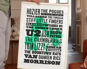 Könnte beinhalten: Ein rechteckiger gerahmter Druck mit einer großen grünen Kleeblattgrafik, überlagert mit schwarzem Text, der verschiedene Musikkünstler auflistet, darunter Hozier, The Pogues, U2, The Cranberries, Thin Lizzy, Sinead O'Connor, Van Morrison und Damien Rice.