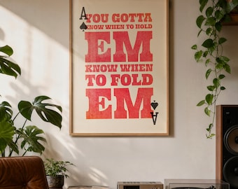 Peut inclure: Une affiche encadrée avec le texte "You Gotta Know When to Hold 'Em, Know When to Fold 'Em" en lettres rouges. L'affiche comprend un symbole de pique et de carreau. L'affiche est dans un cadre en bois et est accrochée à un mur blanc.