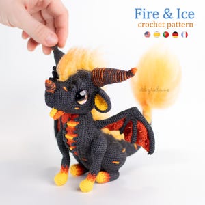 May include: A crocheted dragon with a black body, orange and yellow accents, and large, expressive eyes. The dragon has horns, wings, and a fluffy tail. The text "Fire & Ice crochet pattern" is at the top.