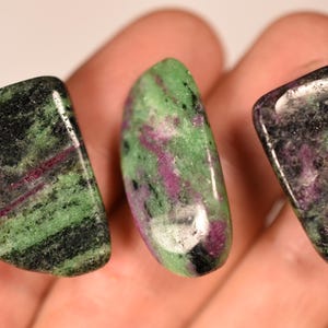 Può includere: Tre pietre di zoisite levigate, di colore verde, nero e rosa. Le pietre sono lisce e lucidate.