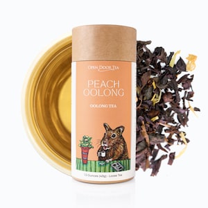 May include: A brown cardboard tube with a peach oolong tea label. The label features a cartoon hamster drinking tea and the text "Open Door Tea", "Peach Oolong", and "Oolong Tea". The tube contains 1.5 ounces (43g) of loose leaf tea.