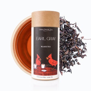 May include: A brown cardboard tube with a red cardinal illustration and the text "Open Door Tea Earl Gray Black Tea 2 Ounces (57g) - Loose Tea".